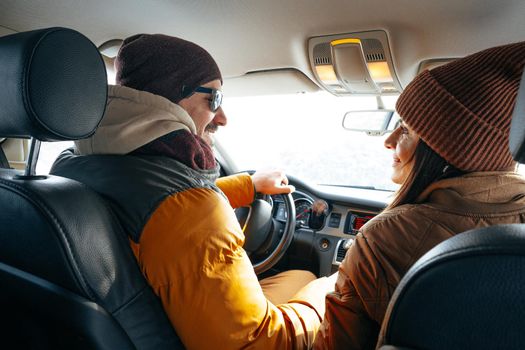 Family couple sitting in car in winter clothes iin snow forest, close up