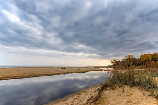 Small lake near sea sand with sky reflection