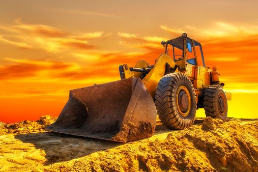 A stopping yellow excavator at an incredibly beautiful sunset