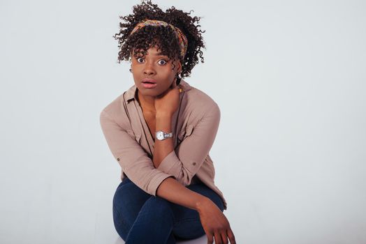 Surprised face. Beautiful afro american girl with curly hair in the studio with white background.