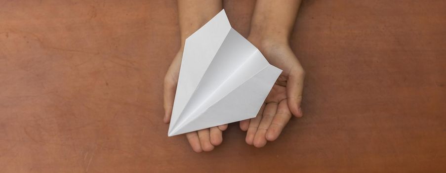 Child's Dream. Child's hand launching white paper airplane.