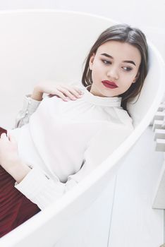 Portrait of fashionable women in red skirt and white blouse posing in a bath. Girl with a big red lips
