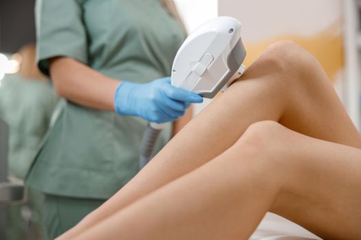 Closeup of legs laser photo epilation with ipl machine in beauty salon. Hair removal, cosmetology