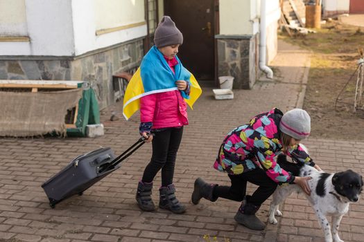 Ukraine military migration. two little girls with a suitcase. Flag of Ukraine, help. Crisis, military conflict.