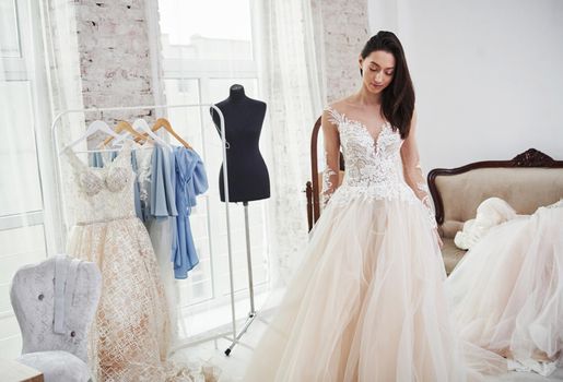 Standing in front of the mirror. The process of fitting the dress in the studio of hand crafted clothes.