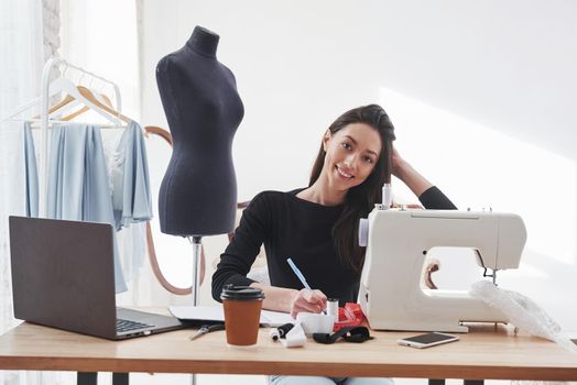 In love with her job. Female fashion designer works on the new clothes in the workshop.