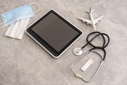 Medical equipment: stethoscope and tablet on grey background.