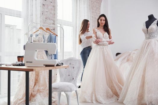 Helping the bride. The process of fitting the dress in the studio of hand crafted clothes.