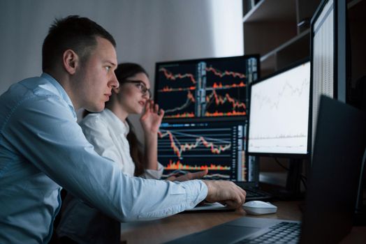 Focused young people. Team of stockbrokers are having a conversation in a office with multiple display screens.