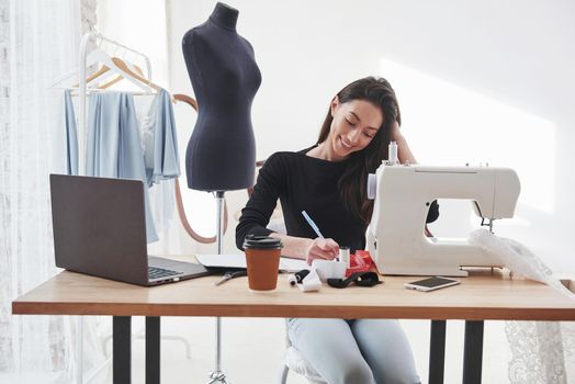 Front view. Female fashion designer works on the new clothes in the workshop.