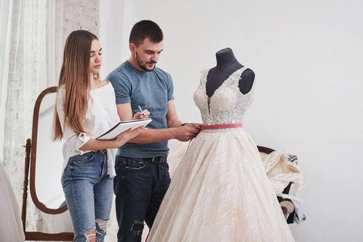 People measures width of dress and makes calculations for an order.