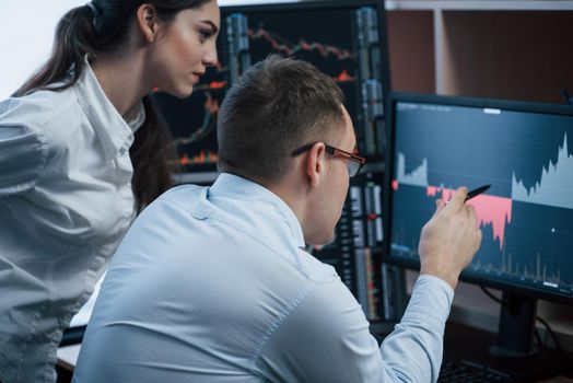 Team of stockbrokers are having a conversation in a office with multiple display screens.