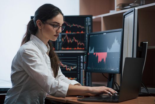 Team of stockbrokers are having a conversation in a office with multiple display screens.