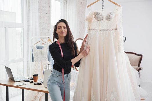 Showing off perfect dress. Female fashion designer works on the new clothes in the workshop.