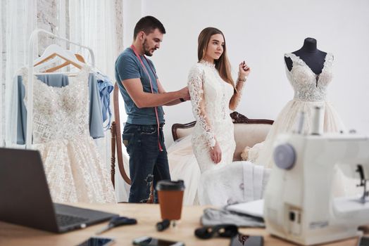 Guy helps the bride. The process of fitting the dress in the studio of hand crafted clothes.