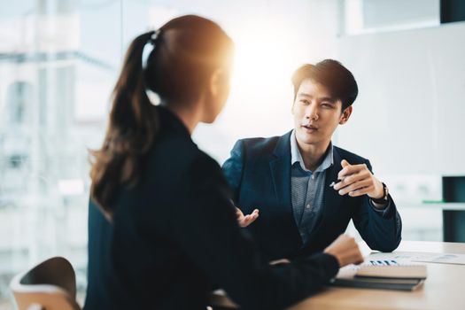 Two diverse asian business people discussing work together in an office.