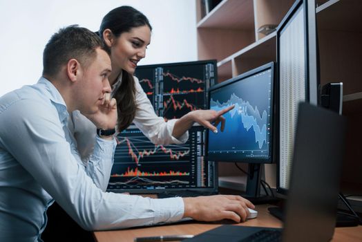 Team of stockbrokers are having a conversation in a office with multiple display screens.