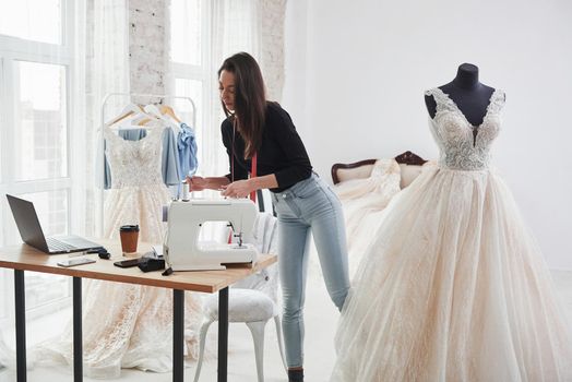Remains few moves and it will be done. Female fashion designer works on the new clothes in the workshop.