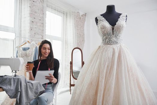 Finally rest time. Female fashion designer works on the new clothes in the workshop.