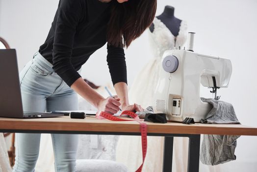 Particle view. Female fashion designer works on the new clothes in the workshop.