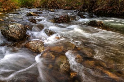 beautiful motion blur view of flowing water in the river with stones 