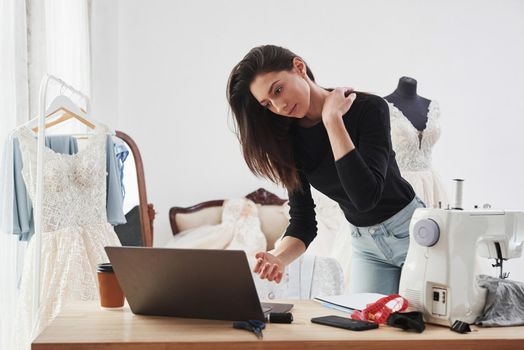 Using laptop. Female fashion designer works on the new clothes in the workshop.