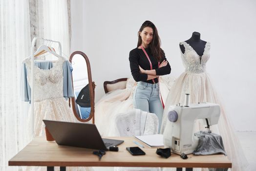 Nice day in clean room with proud owner. Female fashion designer works on the new clothes in the workshop.