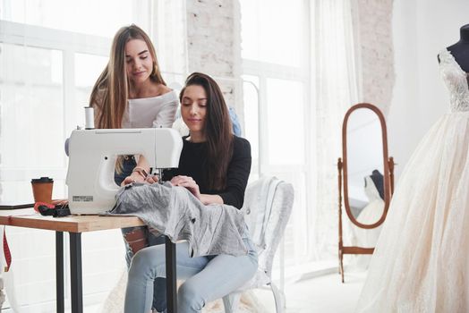 Calm mood. Two female fashion designers works on the new clothes in the workshop.