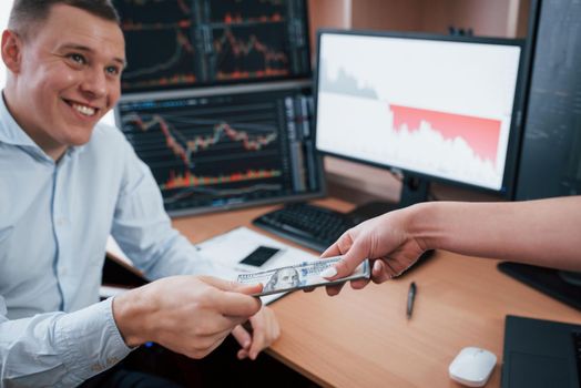 Thank you for your job. Day of salary in the modern office with screens with graphs on them.