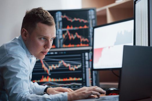 Thinks what to do next. Man working online in the office with multiple computer screens in index charts.
