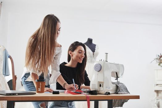 Our dress will be perfect. Two female fashion designers works on the new clothes in the workshop.