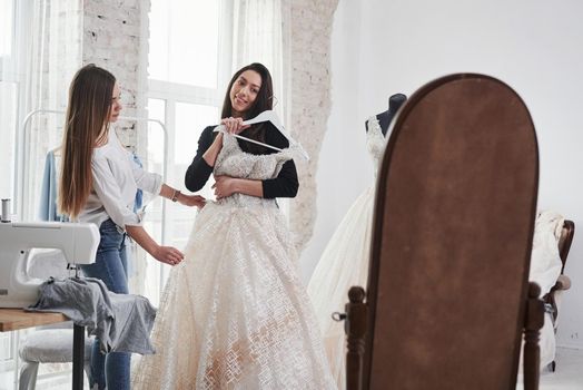 Looking to the mirror. The process of fitting the dress in the studio of hand crafted clothes.