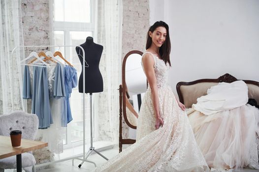 Cute brunette smiling. The process of fitting the dress in the studio of hand crafted clothes.