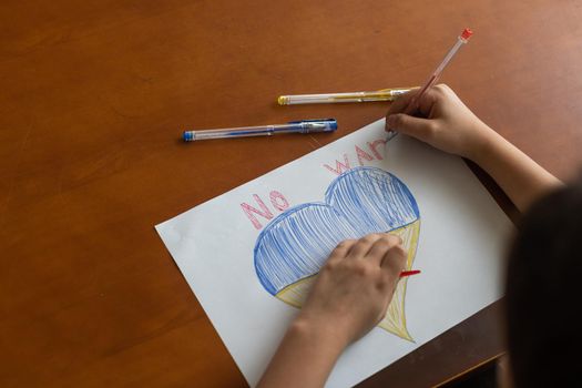 children's drawing, flags of ukraine are drawn on a sheet, children's hands hold a heart made, war between countries, peace concept.