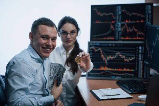 Team of stockbrokers are having a conversation in a office with multiple display screens.