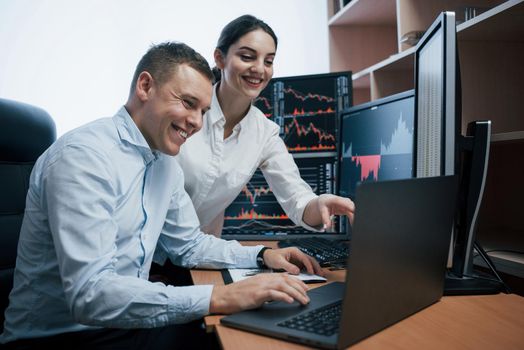 Team of stockbrokers are having a conversation in a office with multiple display screens.