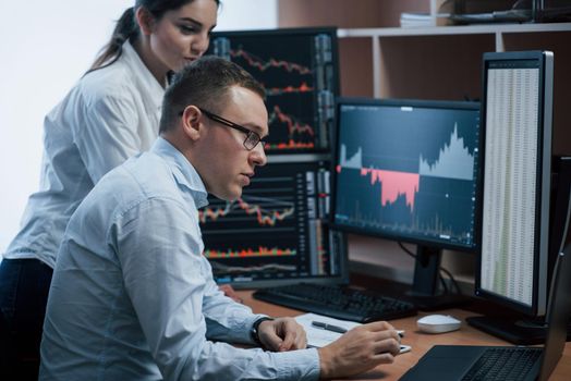 Making smart decisions. Team of stockbrokers are having a conversation in a office with multiple display screens.