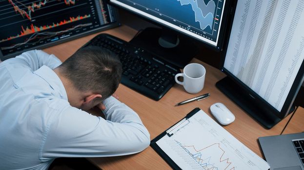 In stress because unexpected fail. Man working online in the office with multiple computer screens in index charts.