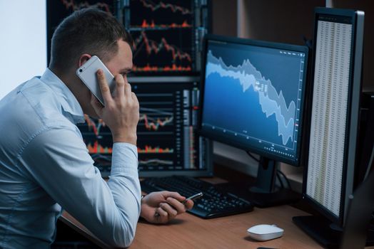 Alone in the room. Man working online in the office with multiple computer screens in index charts.