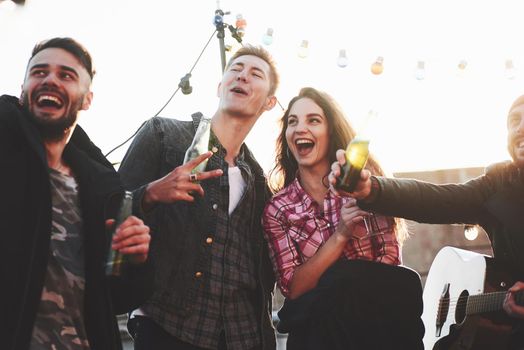 Gesturing and smiling. Group of young cheerful friends having fun while takes selfie on the roof with decorate light bulbs.