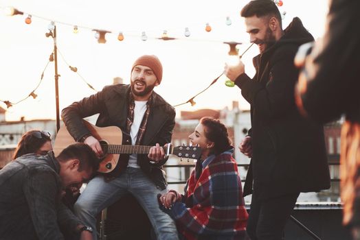 It's good to be together. Friends have fun at rooftop party with decorative colored light bulbs.