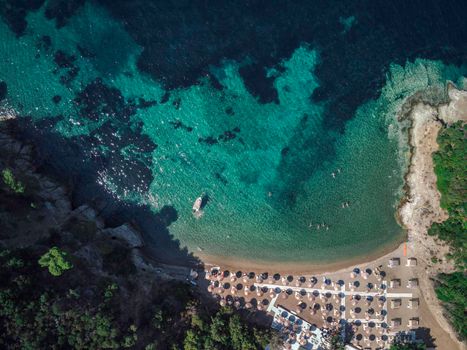 Turquoise water Mediterranean beach with sea umbrellas aerial drone view in Sithonia Chalkidiki peninsula Greece.