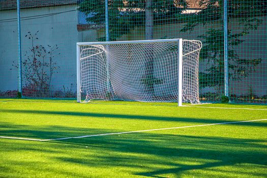 Empty white gate on the football field with green grass. Concept of training in football sections and schools, preparation for competitions and matches.