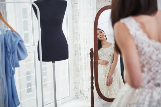 Sincere smile. The process of fitting the dress in the studio of hand crafted clothes.