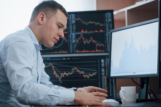 Man working online in the office with multiple computer screens in index charts.