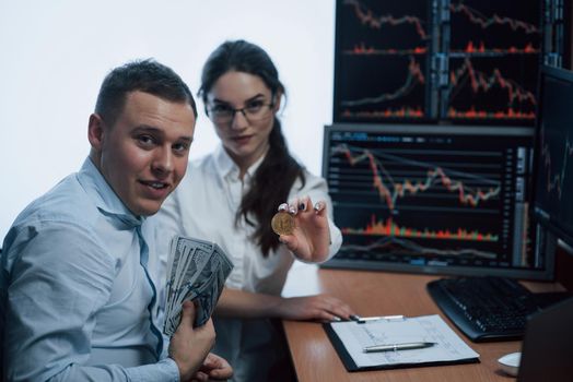 Team of stockbrokers are having a conversation in a office with multiple display screens.