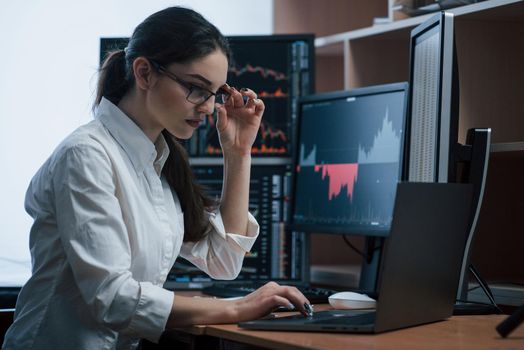 Big money depends on the success of this project. Woman working online in the office with multiple computer screens in index charts.