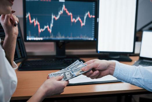 Day of salary in the modern office with screens with graphs on them.