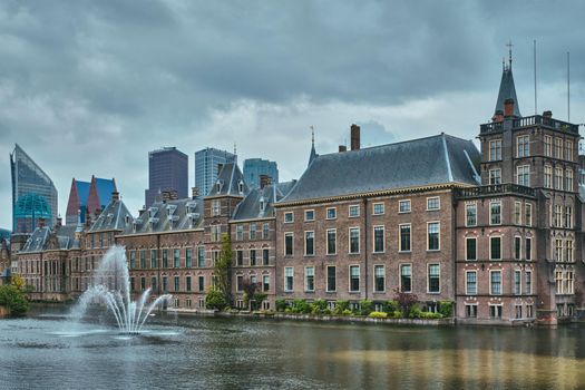 View of the Binnenhof House of Parliament and the Hofvijver lake with downtown skyscrapers in background. The Hague, Netherlands