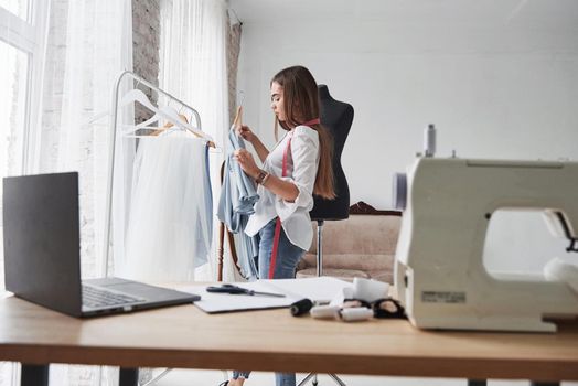 Laptop on the table and modern technology. Female fashion designer works on the new clothes in the workshop.